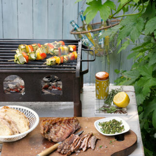 Gegrilltes Lammfleisch auf Holzbrett & Käse-Gemüsespiesse auf Grill Grillen Unterseite Holzkohle-Grill