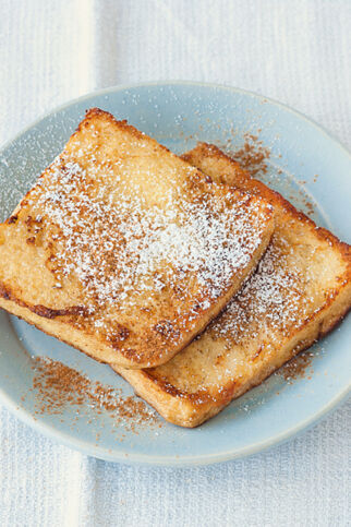 Zwei Scheiben French Toast auf einem Teller mit Puderzucker. French Toast