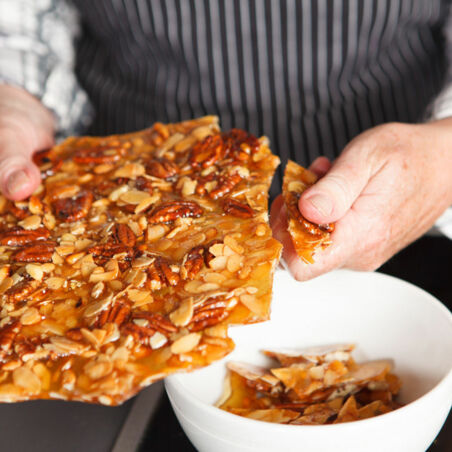 Fertiges Nusskrokant wird in Stücke gebrochen Nusskrokant