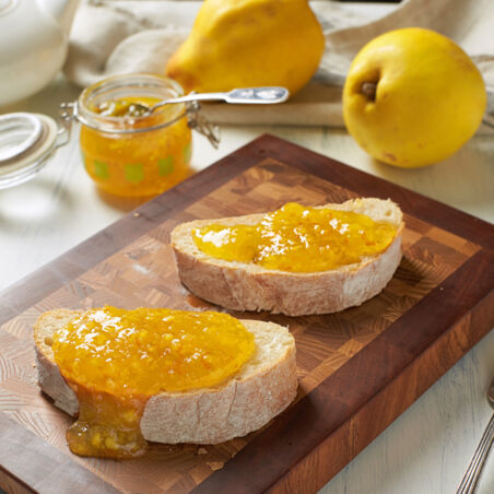 Brotscheiben mit Quittenmarmelade bestrichen auf Holzbrett - Grundrezept Quittenmarmelade Quittenmarmelade auf Brot